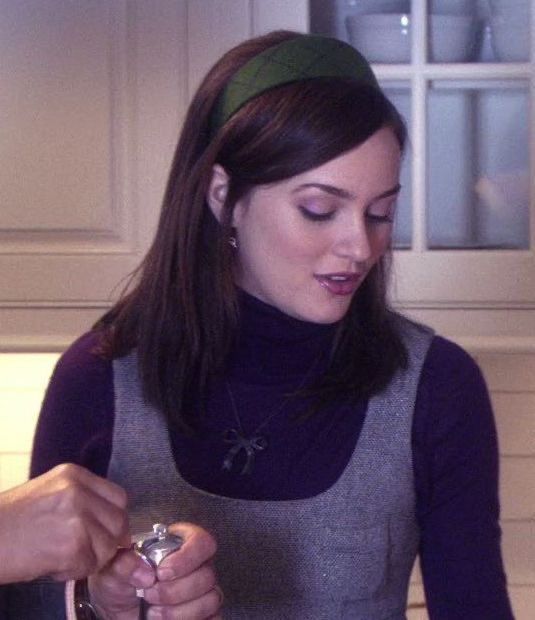 a woman in a gray and purple dress is holding a silver object while looking down at it