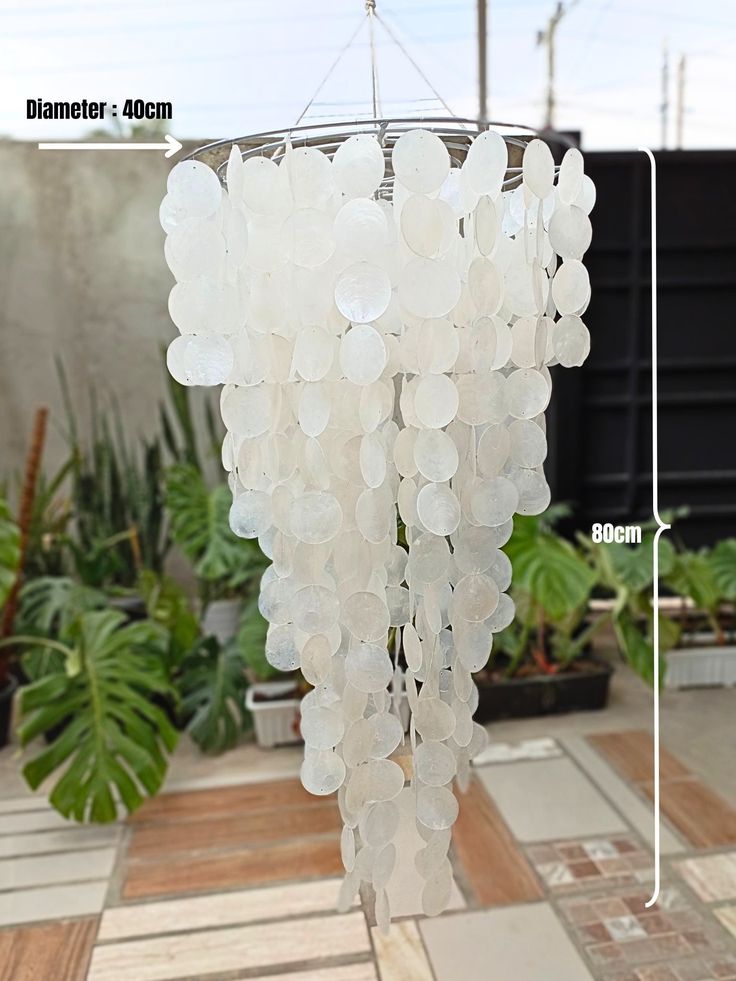 a chandelier made out of plastic bottles hanging from a ceiling in a garden