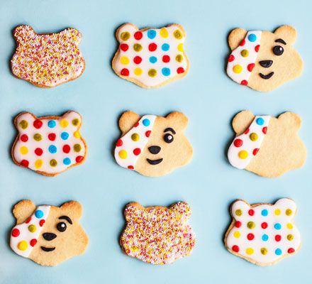 decorated cookies in the shape of teddy bears on a blue background with sprinkles