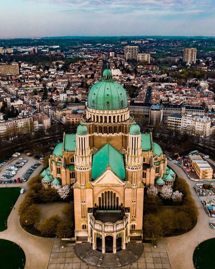 an aerial view of a large building in the middle of a city with lots of green roofs