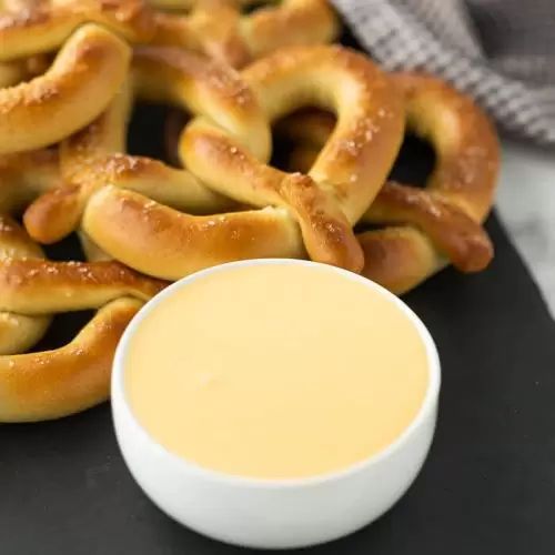 some pretzels on a black table next to a small bowl of dipping sauce