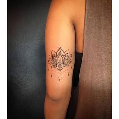 a woman's arm with a lotus tattoo on the left side of her arm