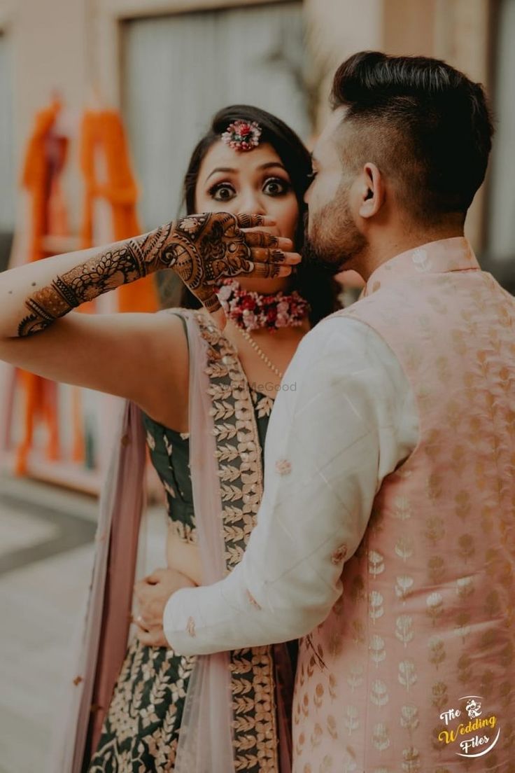 a bride and groom are posing for the camera while holding their hands up to their face