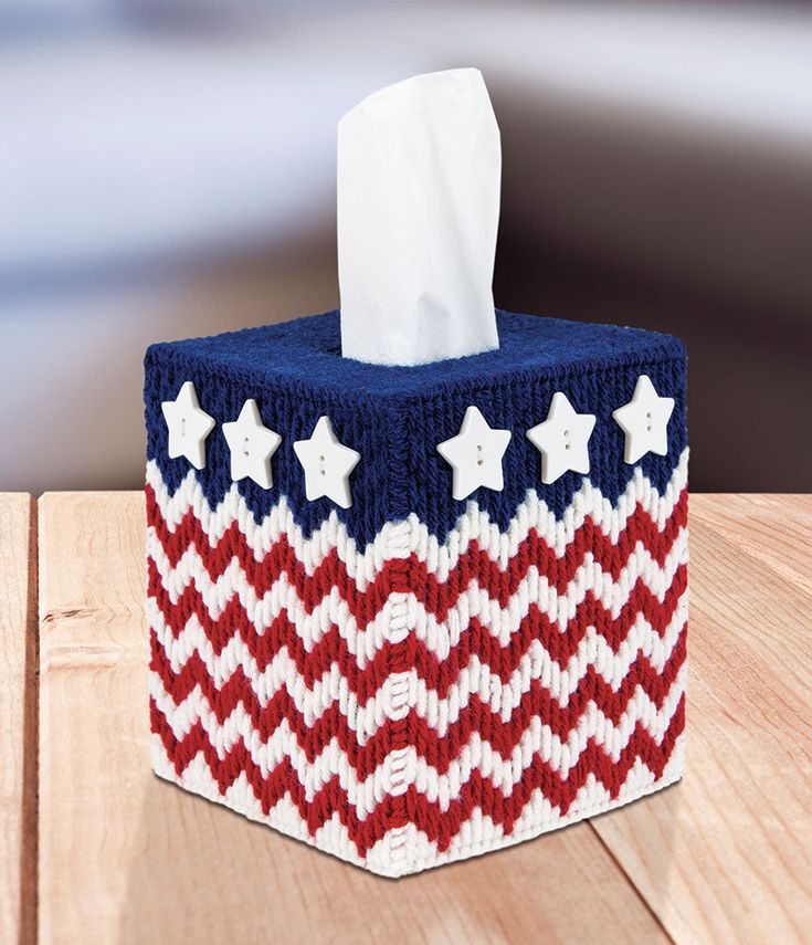 a red, white and blue tissue dispenser sitting on top of a wooden table