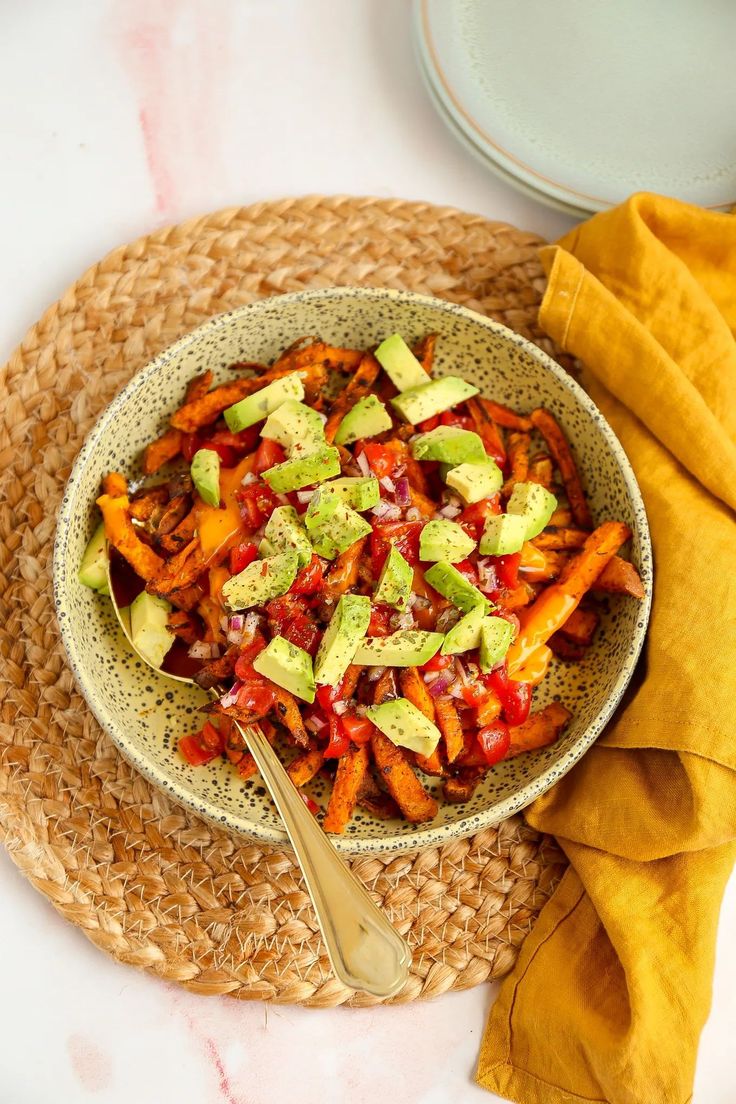 a bowl filled with carrots and avocado on top of a table