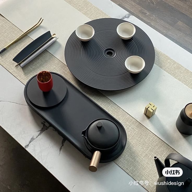 a table topped with black plates and cups