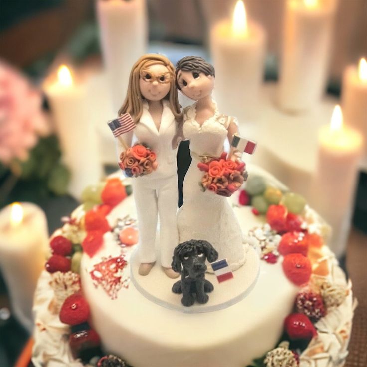 a wedding cake with two bride and groom figurines next to each other, surrounded by candles