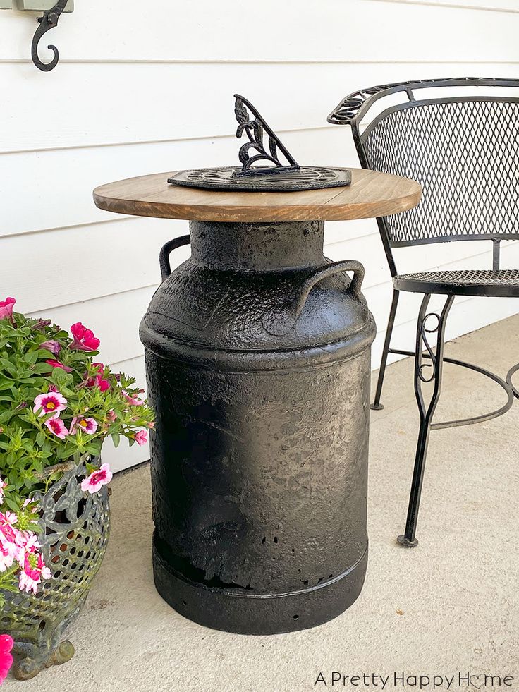 an outdoor table and chair sitting next to a potted planter with flowers on it