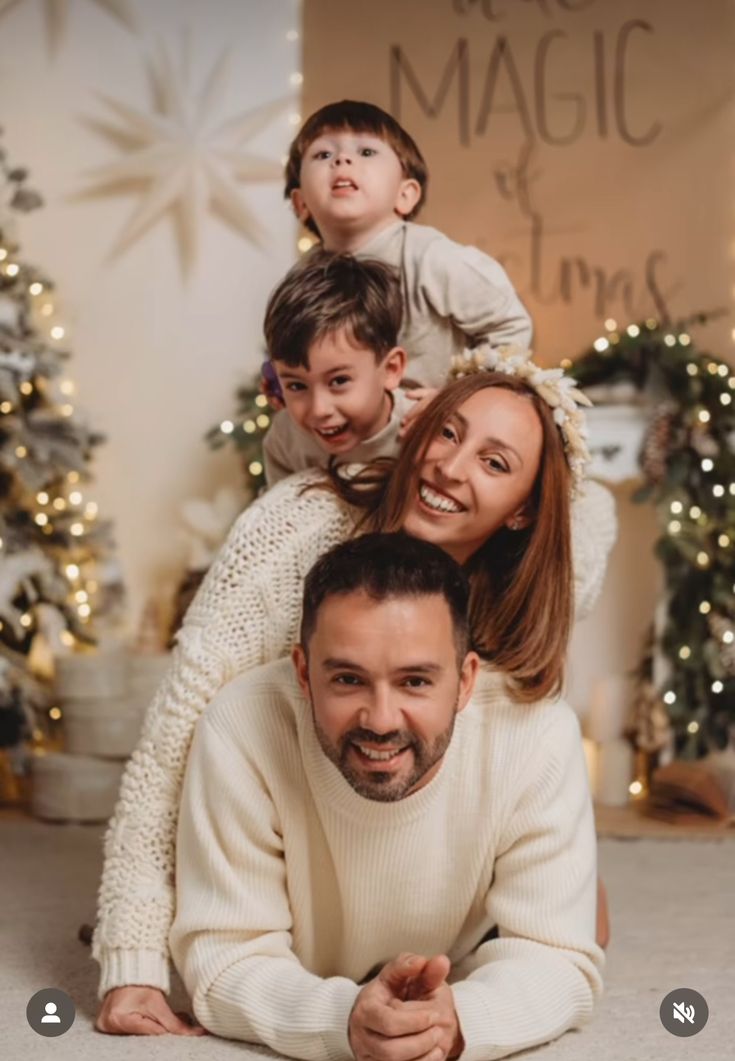 a family posing for a photo in front of christmas tree with lights and snowflakes