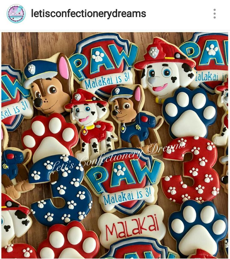 cookies decorated with paw patrol and paw's name are displayed on a wooden table