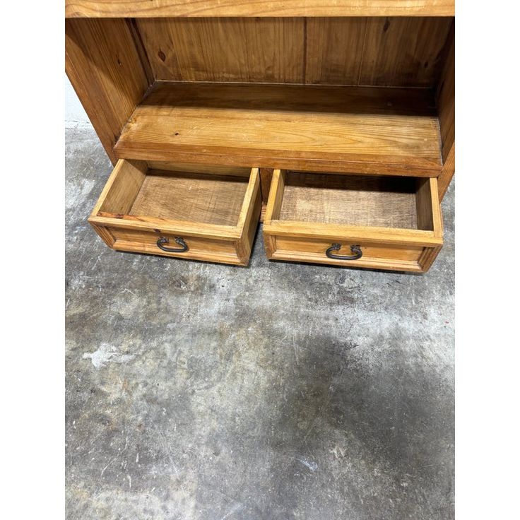 two wooden boxes sitting on top of a cement floor next to each other with lids open