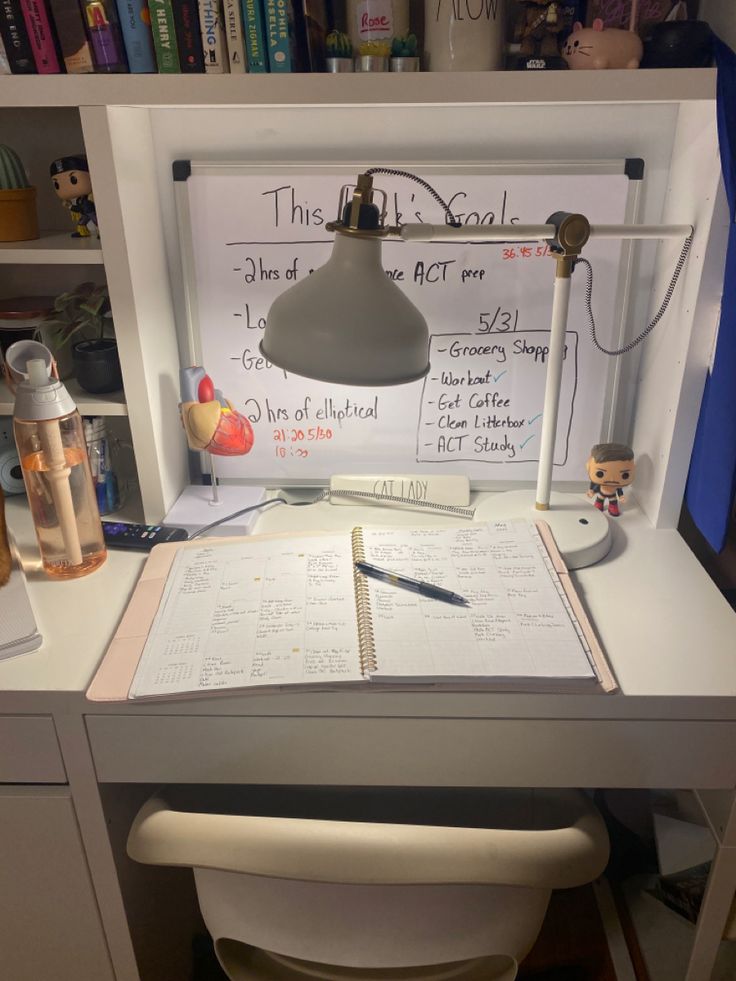 an office desk with a lamp, notebook and pen sitting on it's side