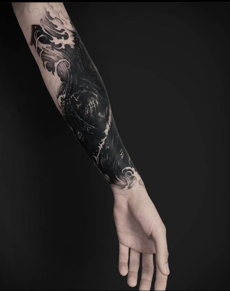 a man's arm with a black and white tattoo design on the left forearm