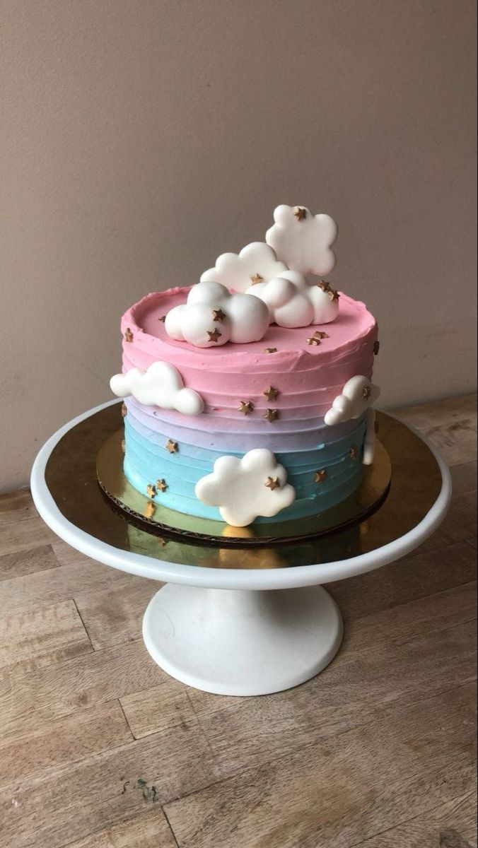 a multi - colored cake with clouds and stars on top is sitting on a plate