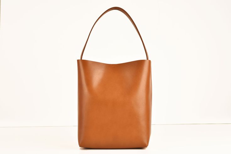 The Square Bucket Bag is made of supple, vegetable-tanned cowhide and has great support. A relaxed and spacious companion for every day. With snap fastener Dimensions of the bag: Height: 32 cm Width: 24 cm Depth: 17 cm Handle length: 53 cm Leather is a natural product, each bag has a different pattern! The Square Bucket Bag is made to order just for you. Therefore, check the dimensions of the bag before ordering. If you need a different handle length or would like other changes, please send me a Bucket Hat Leather, Tan Cowhide, Snap Fasteners, Leather Pattern, Etsy Fashion, Different Patterns, Cognac, Real Leather, Purses And Handbags