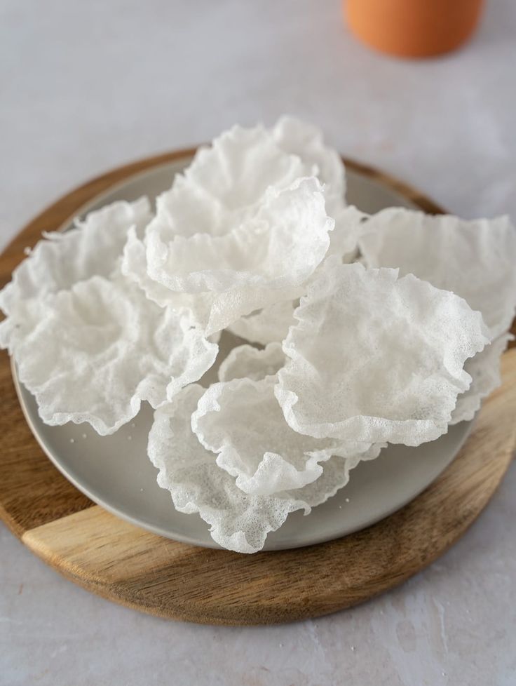 some white flowers are on a plate next to an egg