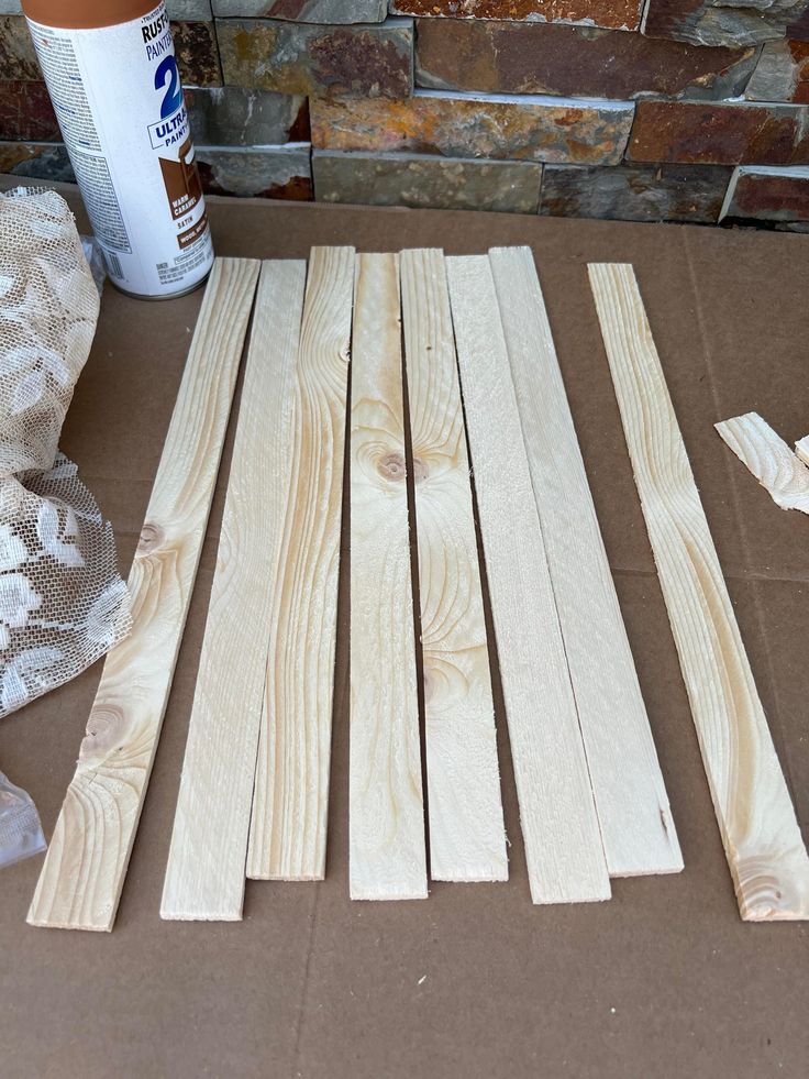 several pieces of wood sitting on top of a cardboard box next to a can of paint