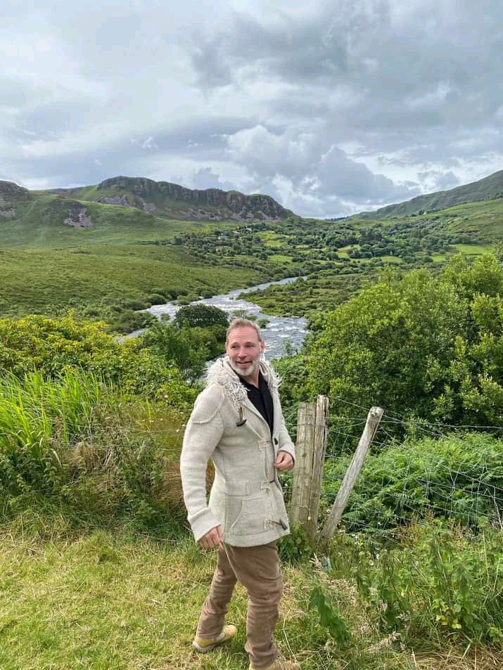 a man standing on top of a lush green hillside