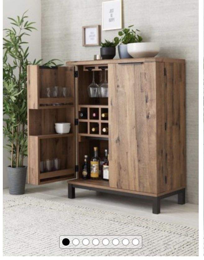 a wooden cabinet with wine glasses on it and a potted plant next to it