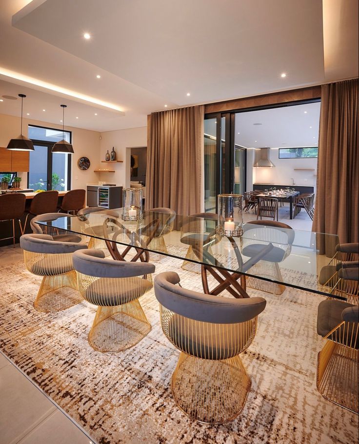 a glass table with chairs around it in front of a large open living room door