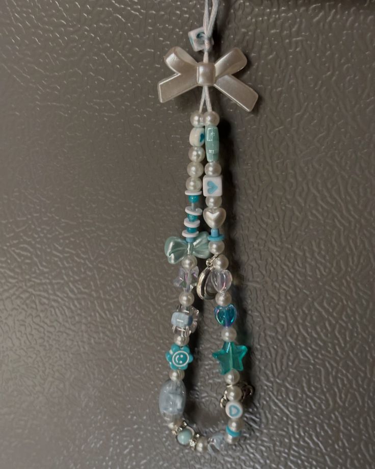 a cross hanging from the side of a wall with beads and charms attached to it