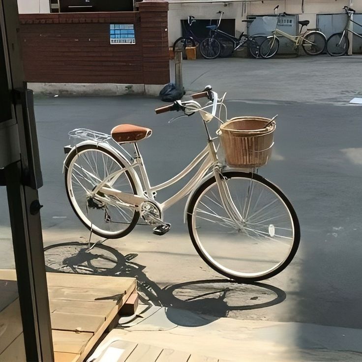 a white bicycle parked on the side of a road next to a building and parking lot