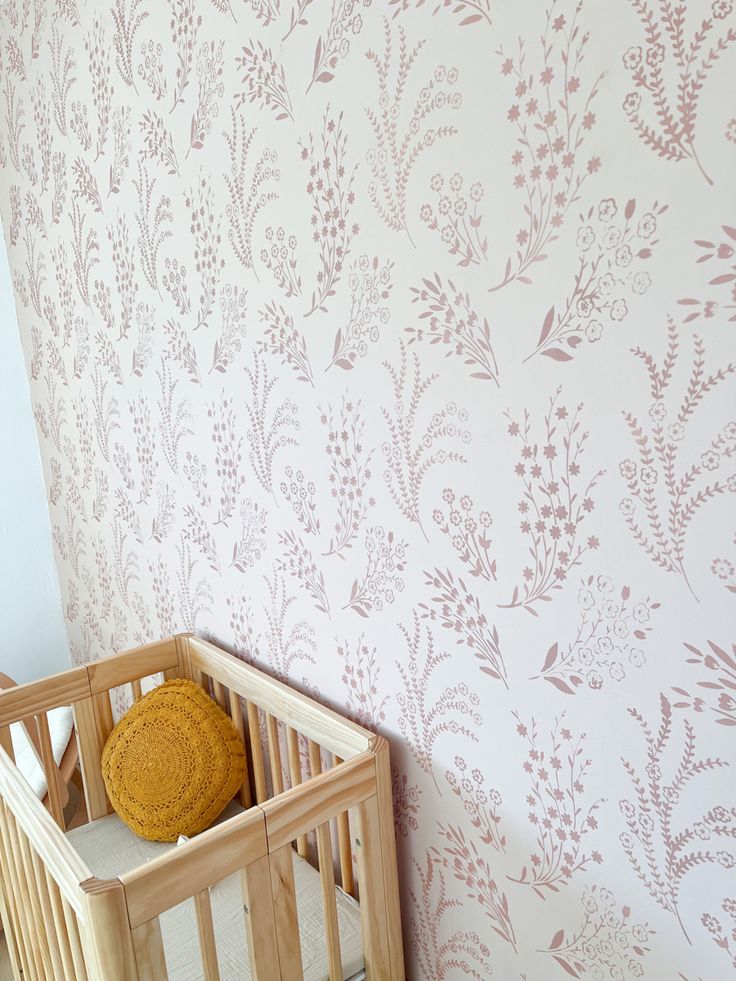 a baby crib in front of a wallpapered with flowers and leaves on it