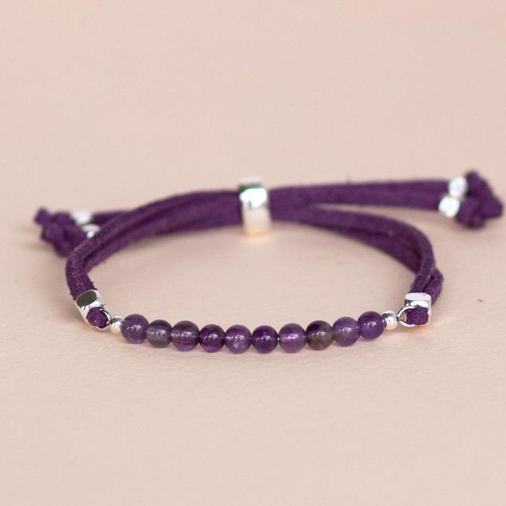 two purple bracelets with silver beads on a pink background