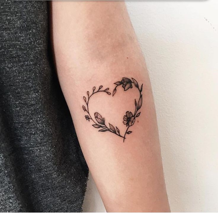 a woman's arm with a heart shaped flower tattoo on the left inner arm