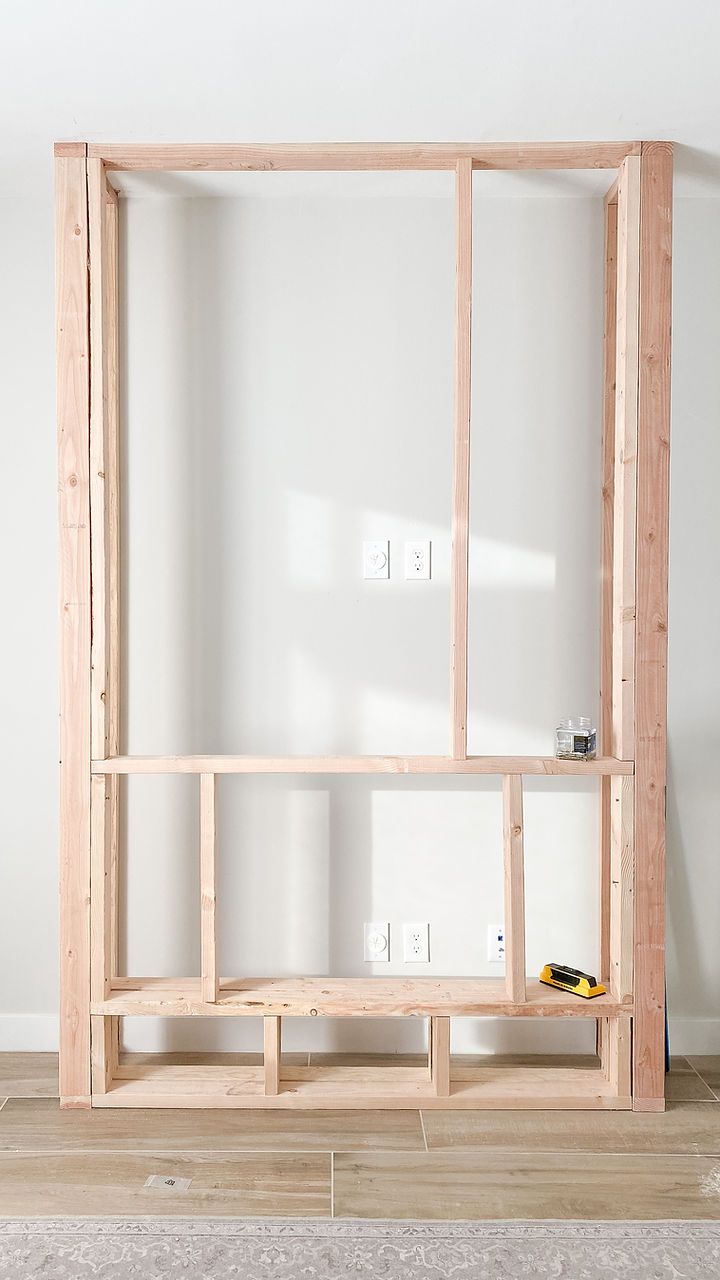 a wooden shelf sitting on top of a hard wood floor next to a white wall