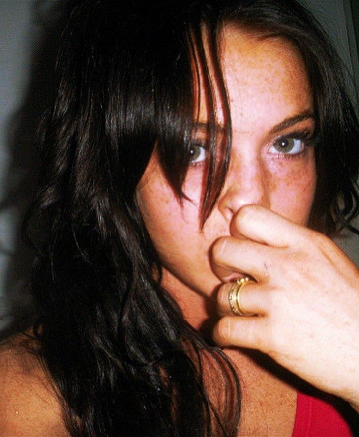 a close up of a person wearing a red shirt and holding her finger to her mouth