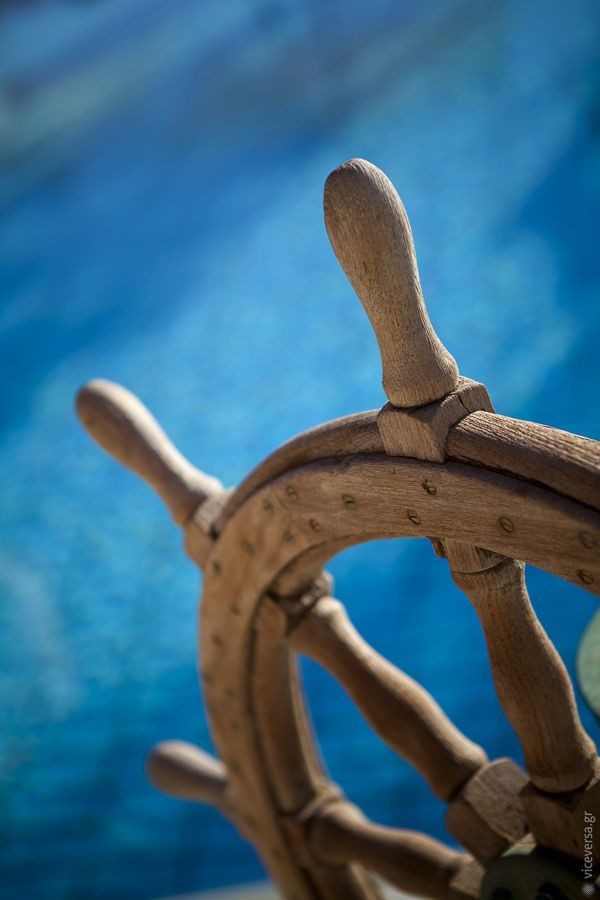 a wooden steering wheel with blue water in the background