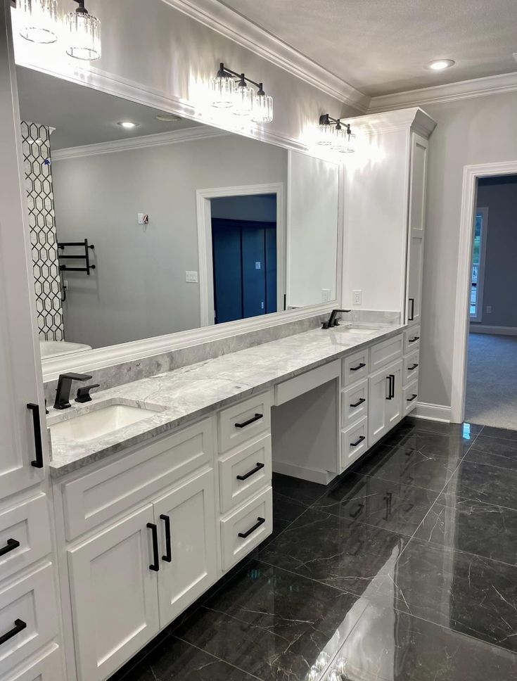 a large bathroom with marble counter tops and white cabinets