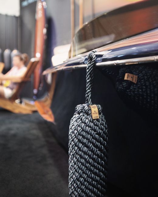 a rope hanging from the side of a boat with people sitting in chairs behind it