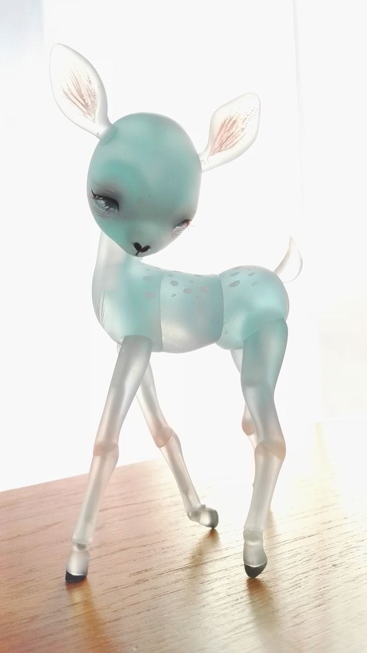 a toy deer is standing on a wooden table with its eyes closed and ears wide open