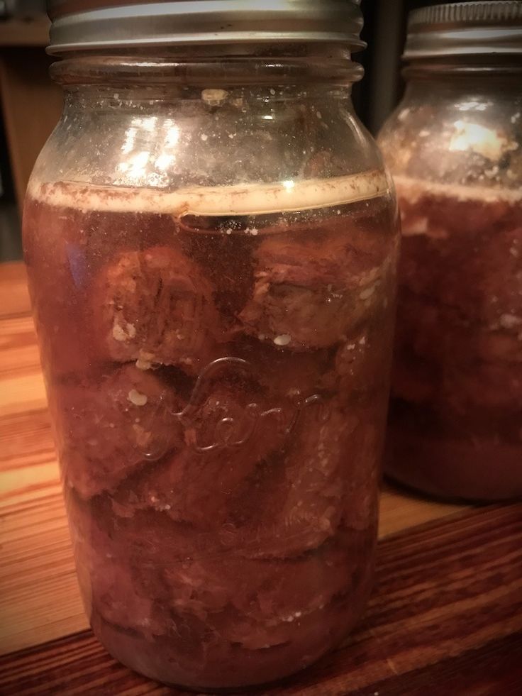 two jars filled with liquid sitting on top of a wooden table