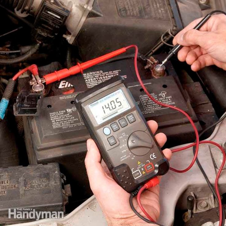 a man is checking the voltages on his car's battery and working on an electronic device