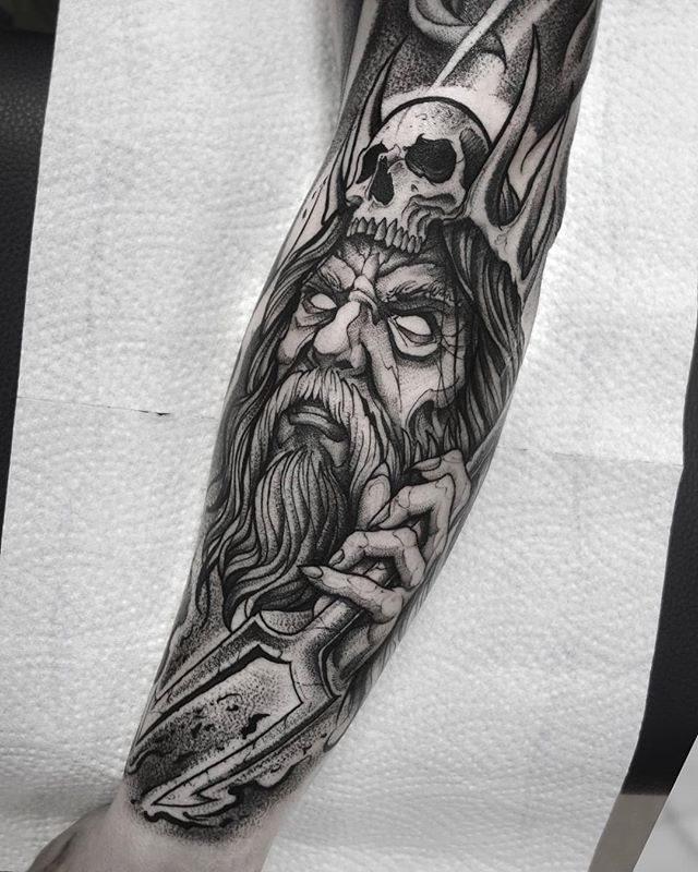 a man's arm with a skull and cross on it, holding a knife