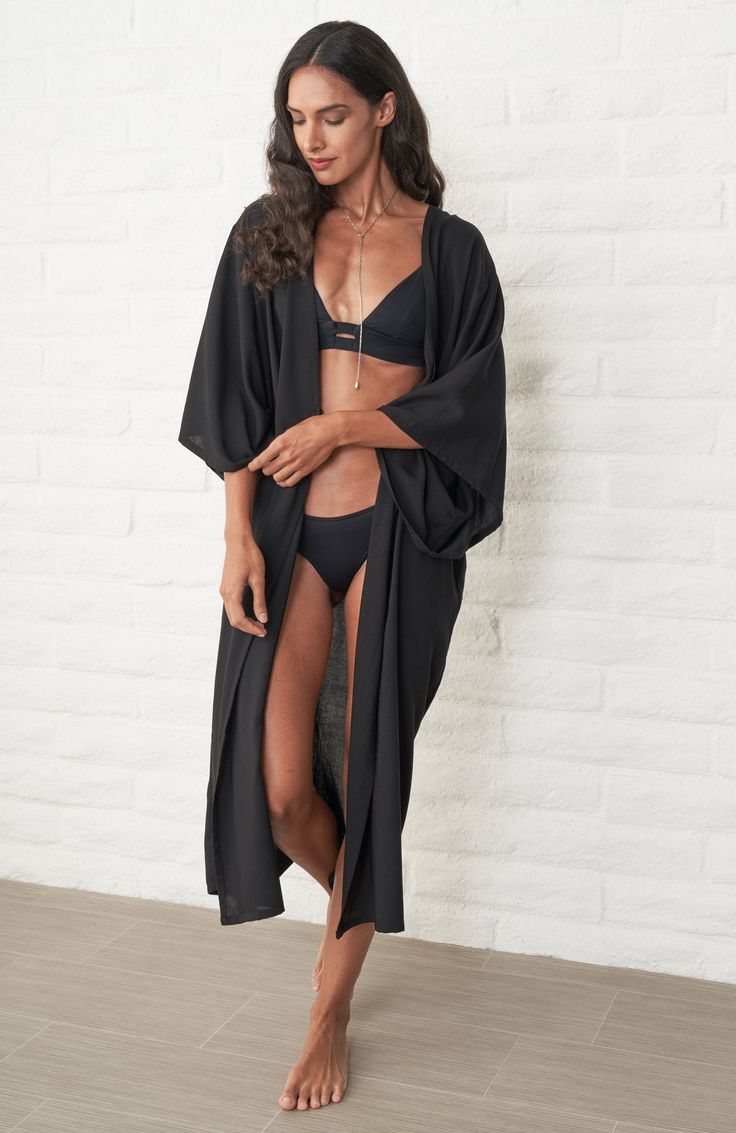 Eco friendly caftans and tunics inspired by the ocean, made on main street. Ethically sourced and locally made in Los Angeles. When we travel, we want clothes that take up minimum space but do maximum work. Meet the Kimono Wrap Duster in Black. It's a dress. It's a duster. It's a robe. It's a cover-up. This one does it all and we couldn't be happier! As a dress, two discreet buttons keep the wrap securely in place and give the dress an architectural drape. The removable self-tie belt can be add Black Long Kimono For Beach Cover-up, Oversized Black Beachwear Cover-up, Oversized Black Beach Cover-up, Oversized Black Cover-up For Beach, Oversized Black Cover-up For Vacation, Black Open Front Kimono For Beach Cover-up, Long Black Kimono For Beach Cover-up, Black Kimono For Beachwear, Long Black Beachwear Kimono