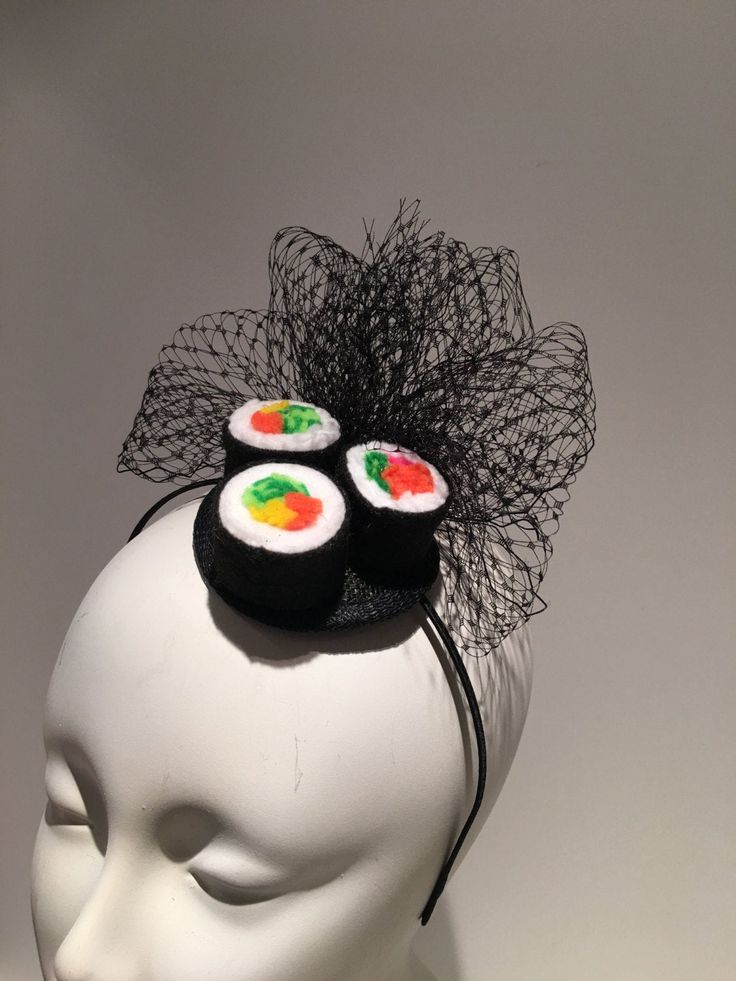 a white mannequin head wearing a black hat with sushi on the side