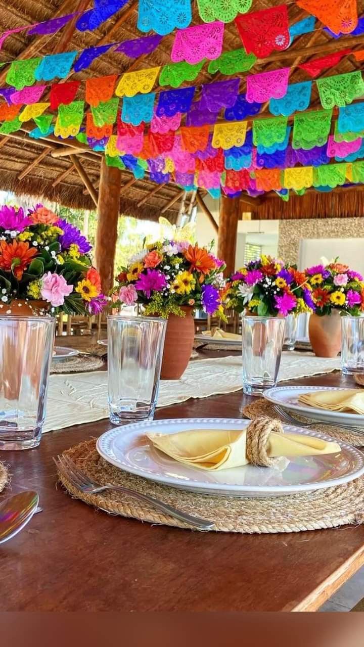 the table is set with colorful flowers and place settings