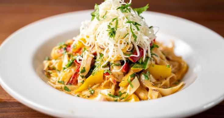 a white plate topped with pasta and veggies covered in parmesan cheese