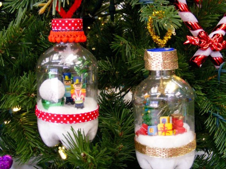 two glass christmas ornaments hanging from a tree with decorations on it's sides and presents in the bottom