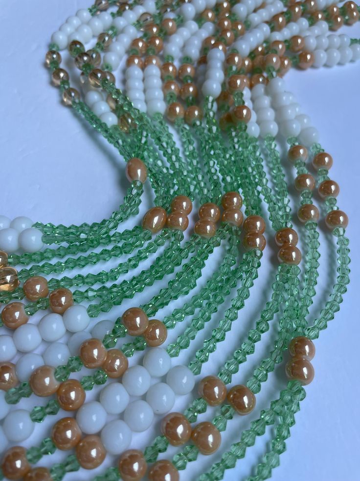 Double Strand Elastic Waist Bead "Kong" features two strands of luminous green crystal glass seed beads, gracefully adorned with larger brown seed bead accents. Immerse yourself in the tranquil allure of nature's palette, as this waist bead brings together vibrant green tones and grounding brown hues to elevate your style with grace and sophistication. 🌿 Luminous Green Radiance: The double strands showcase a vibrant array of green crystal glass seed beads, evoking the freshness and vitality of nature. Green, symbolizing growth and renewal, creates a lively backdrop that exudes a sense of balance and harmony. Interwoven among the strands are larger brown seed bead accents, adding a touch of earthiness and grounding to the design. The brown hues create a harmonious contrast, infusing the wa Green Beaded Chain Beads For Gifts, Elegant Green Polished Beads, Handmade Green Multi-strand Beaded Necklaces, Multi-strand Czech Glass Faceted Beads, Handmade Green Multi-strand Beaded Necklace, Green Tiny Multi-strand Beads, Unique Green Beaded Necklace, Green Multi-strand Beads For Jewelry Making, Traditional Green Beaded Bracelets With Spacer Beads