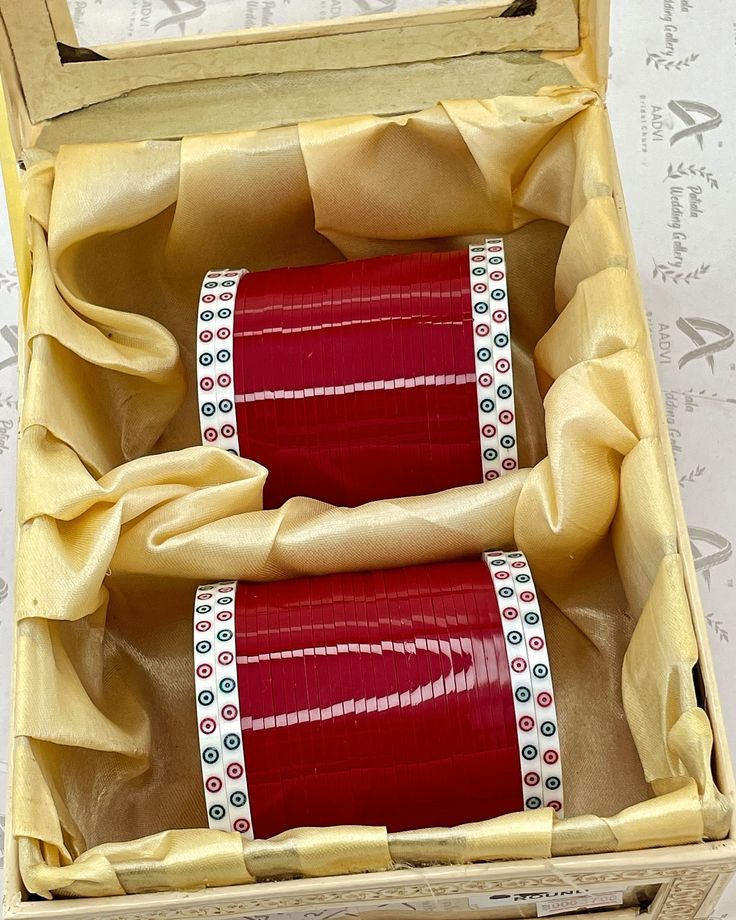 two rolls of red ribbon in a wooden box with ribbons on the inside and outside