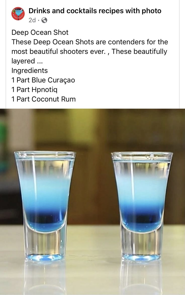 two shot glasses filled with blue liquid sitting on top of a counter next to each other