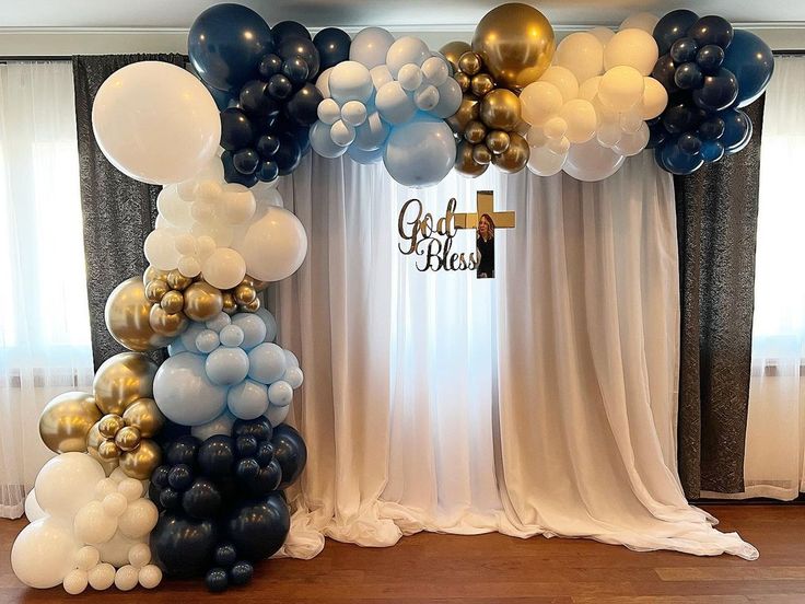 a bunch of balloons that are on top of a table in front of a curtain