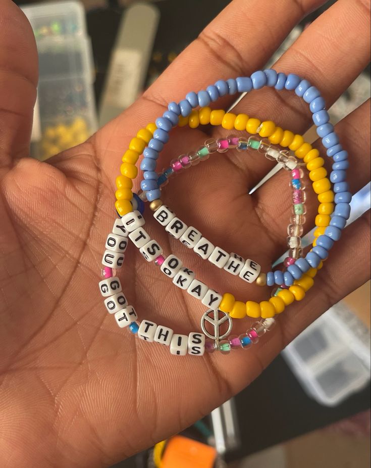 a person holding three bracelets with words written on them in different colors and shapes