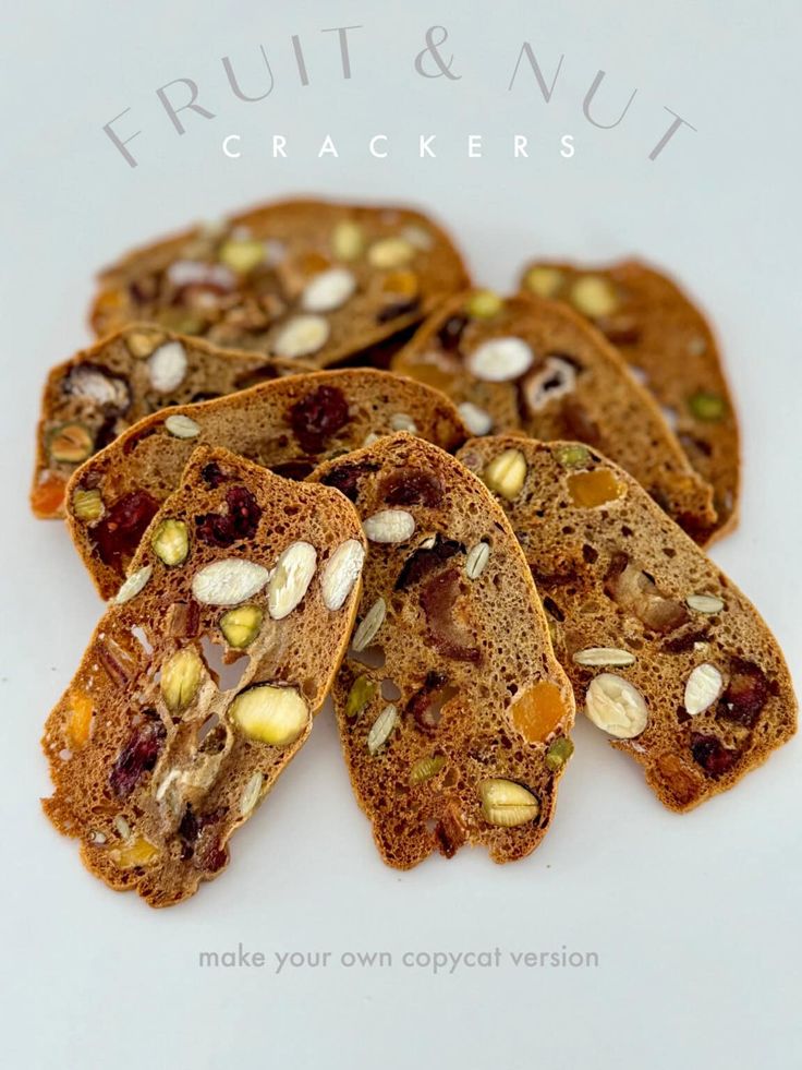 five pieces of bread with nuts and raisins on top, sitting on a white surface