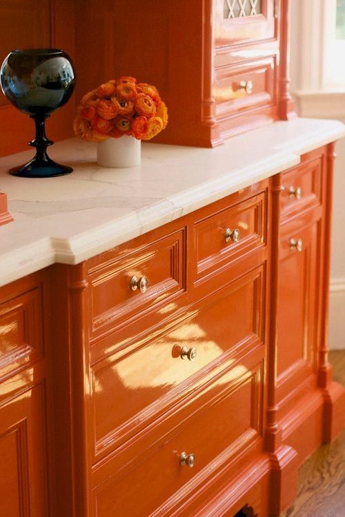 an orange cabinet with white marble top and drawers